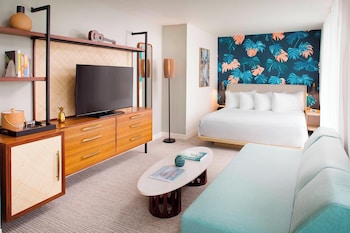 A modern living room with a round table, wicker chairs, a blue sofa, and a red armchair. at The Laylow Waikiki, Autograph Collection