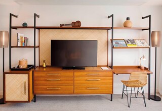 A modern room with a wooden desk, a television, and a bookshelf.