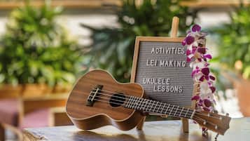 Un ukelele de madera sobre una mesa con un cartel sobre actividades y clases de ukelele.