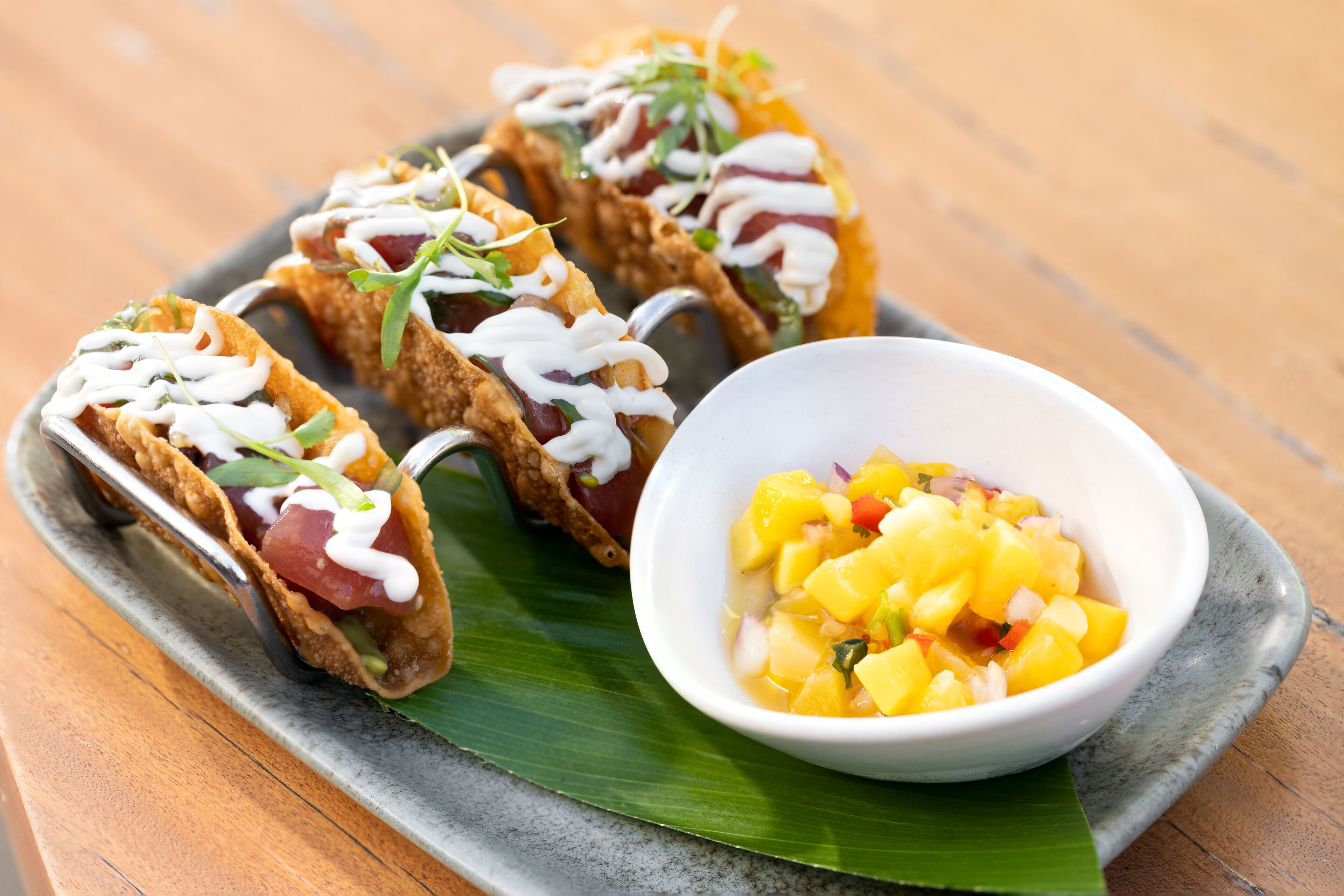 Un plato con tres tacos y un tazón de salsa de mango.