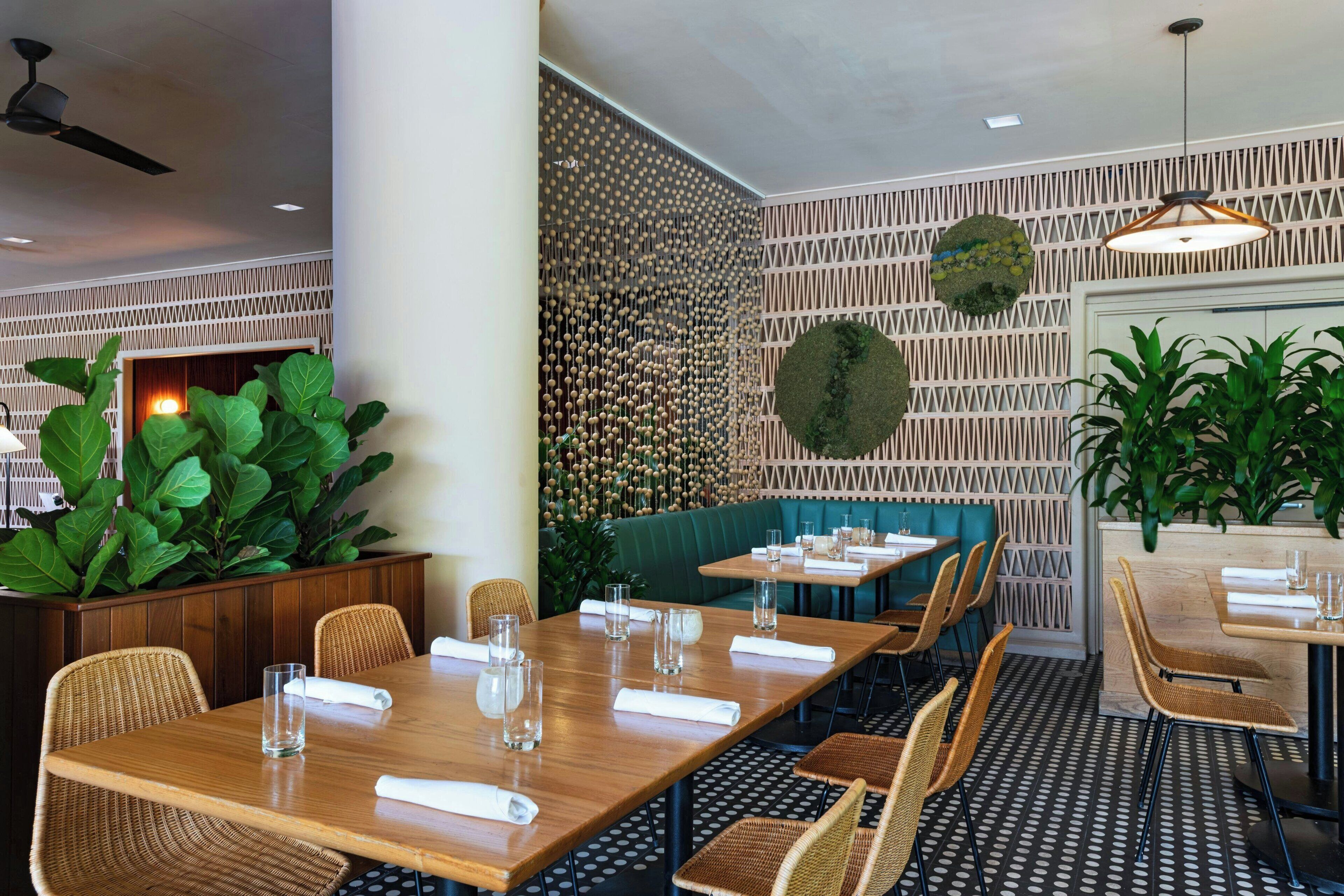 A restaurant interior with wooden tables, wicker chairs, and a green booth.