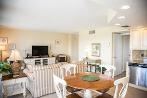 A living room with a sofa, chairs, a TV, and a dining table.