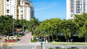 A multi-story hotel with a central courtyard, palm trees, and a clear blue sky.