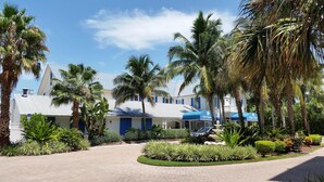 A hotel with a paved courtyard, palm trees, and a blue-roofed building. - Olde Marco Inn 401 (Marco Island)