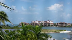 Un hotel frente al mar con varias construcciones, vista al océano y palmeras en primer plano.