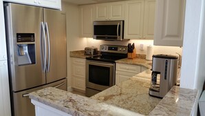 A modern kitchen with stainless steel appliances, including a refrigerator, microwave, and oven.