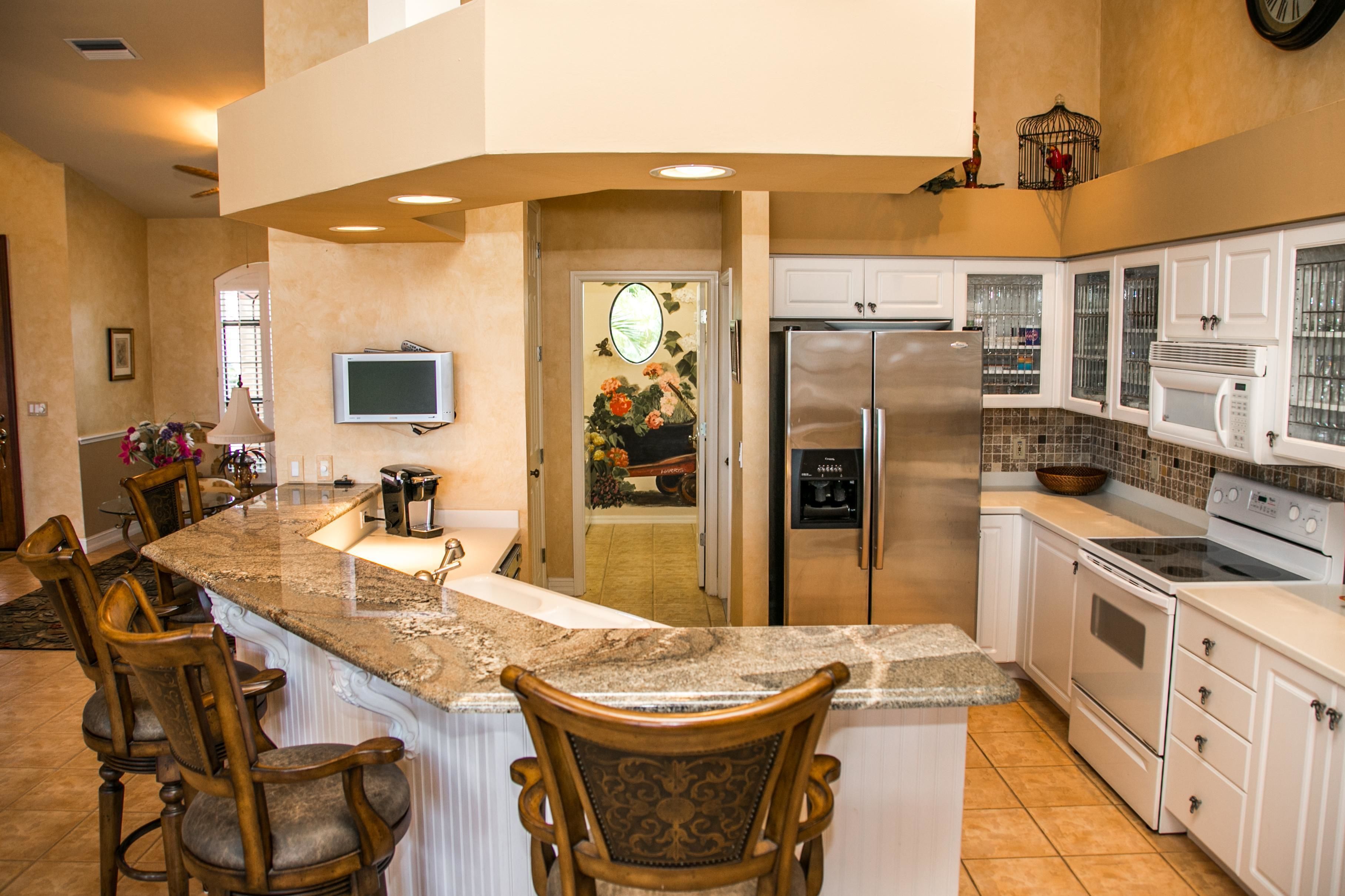 A kitchen with a granite countertop, stainless steel appliances, and white cabinetry.