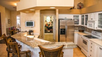 A kitchen with a granite countertop, stainless steel appliances, and white cabinetry.
