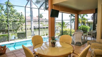 A poolside area with wicker furniture, a round table, and a potted plant.