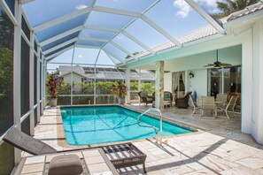 A covered outdoor swimming pool with a glass ceiling, surrounded by patio furniture and a dining area. - 1372 Leland Way (Marco Island)