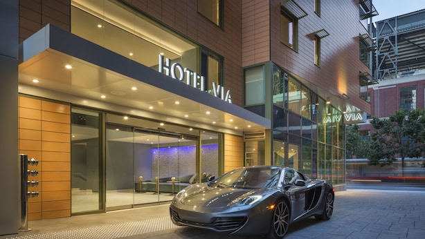 A modern hotel with a sleek exterior and a parked sports car in front. - Hotel VIA (San Francisco)