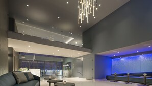 A modern lobby with a curved sofa, round tables, a reception desk, and a large blue wall feature. - Hotel VIA (San Francisco)