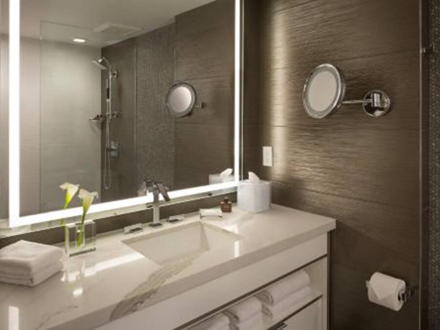 A modern bathroom with a large mirror, a sink, and a shower.