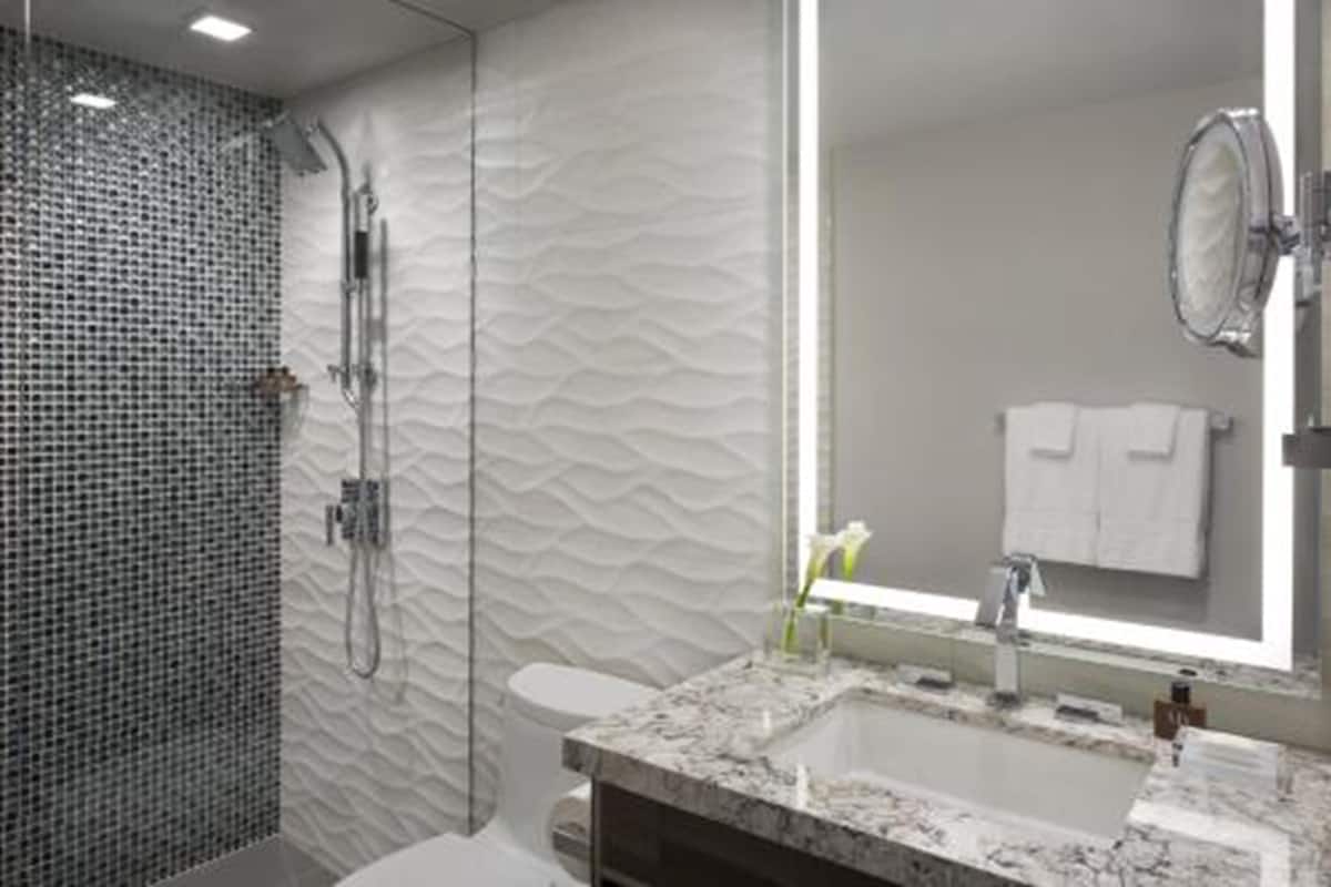 A modern bathroom with a glass shower enclosure, a marble sink, and a large mirror.