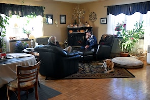 Un salon chaleureux avec une cheminée, des sièges confortables et un chien.
