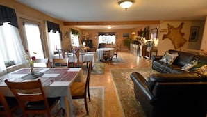 A spacious living room with a black leather sofa, a dining area with a table and chairs, and a kitchen in the background. - Alaska Grizzly Lodge (Fairbanks)