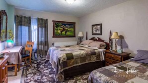 A bedroom with a bed, a desk, a chair, and a painting on the wall. - Alaska Grizzly Lodge (Fairbanks)