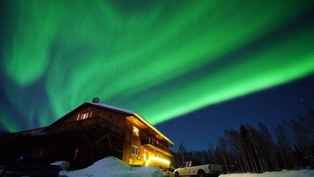 A wooden cabin with a snow-covered ground and a truck parked in front. - Alaska Grizzly Lodge (Fairbanks)