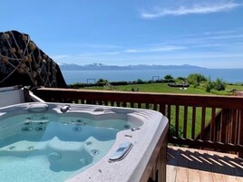 Un jacuzzi en una terraza de madera con vistas a un paisaje montañoso.