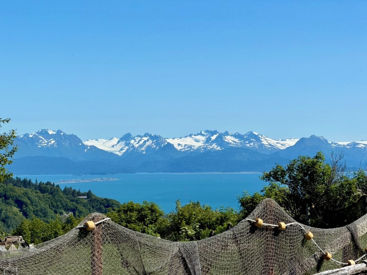 A mountainous landscape with a lake and snow-capped peaks in the background.