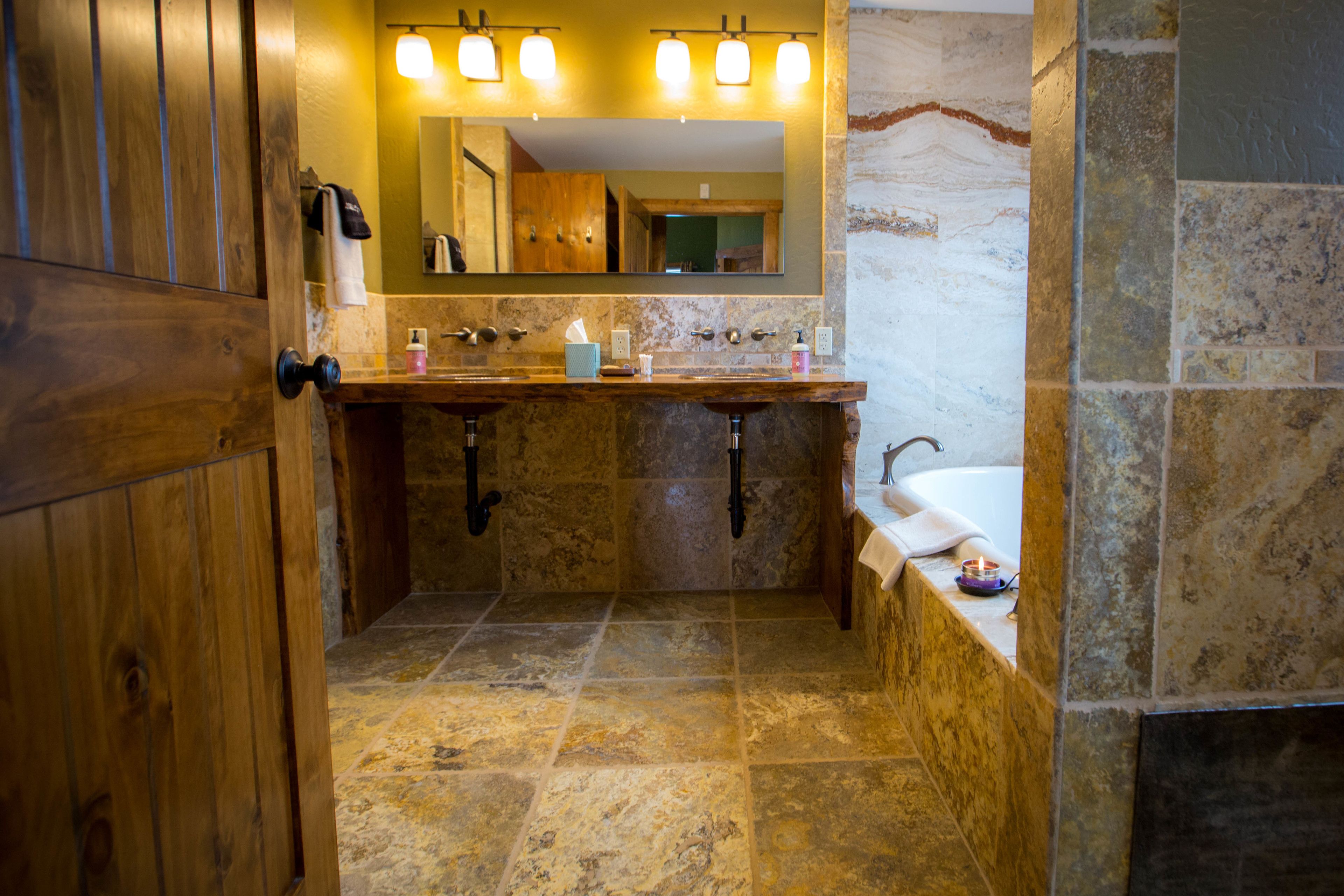Un baño con tocador de madera, lavamanos de mármol y un espejo grande.