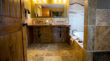 Un baño con tocador de madera, lavamanos de mármol y un espejo grande.
