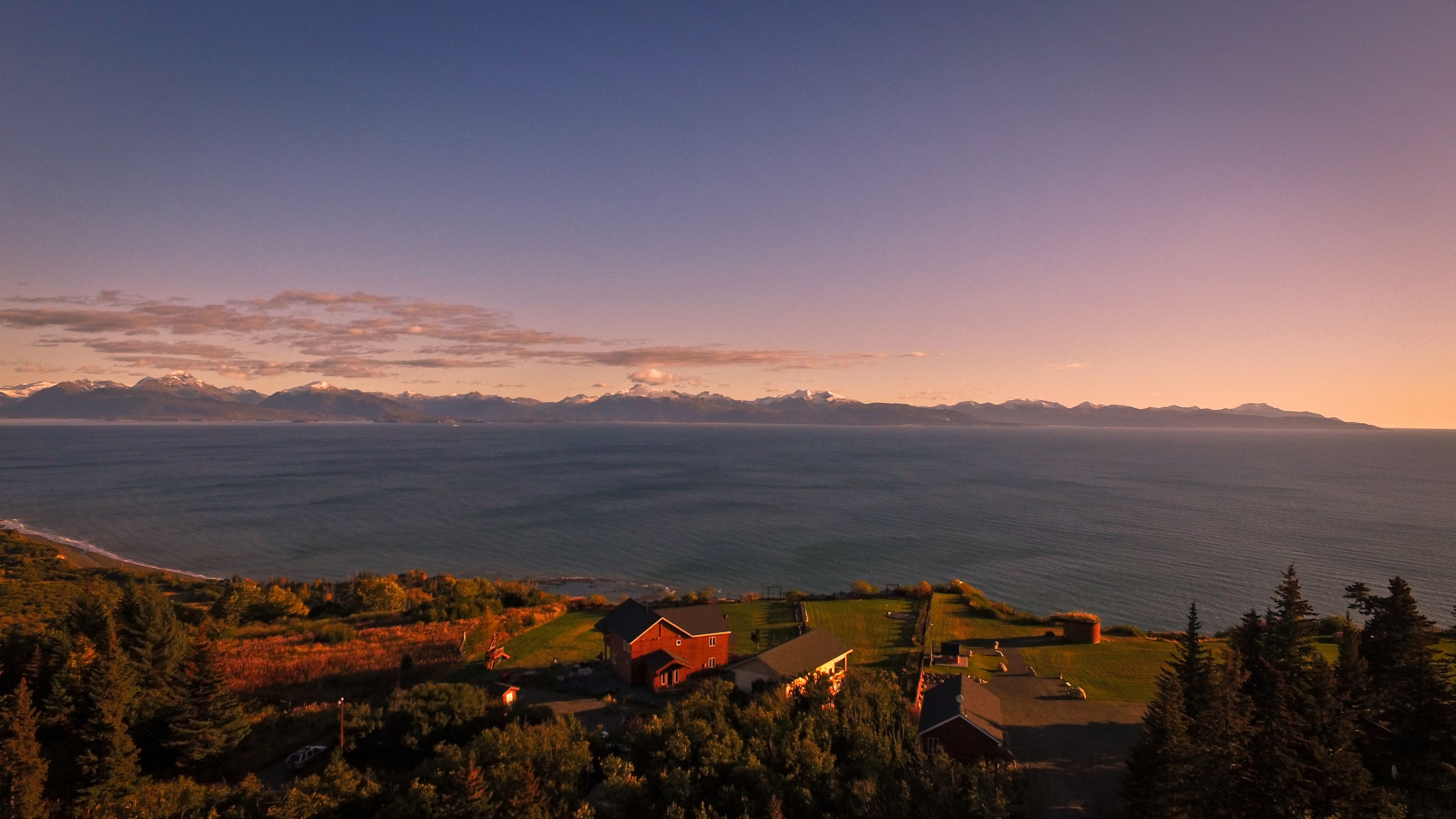 A coastal landscape with houses and mountains in the background.