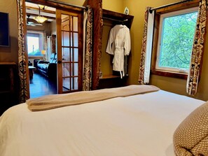 Une chambre à coucher avec un lit, un peignoir suspendu à un porte-manteau et une vue sur un couloir.