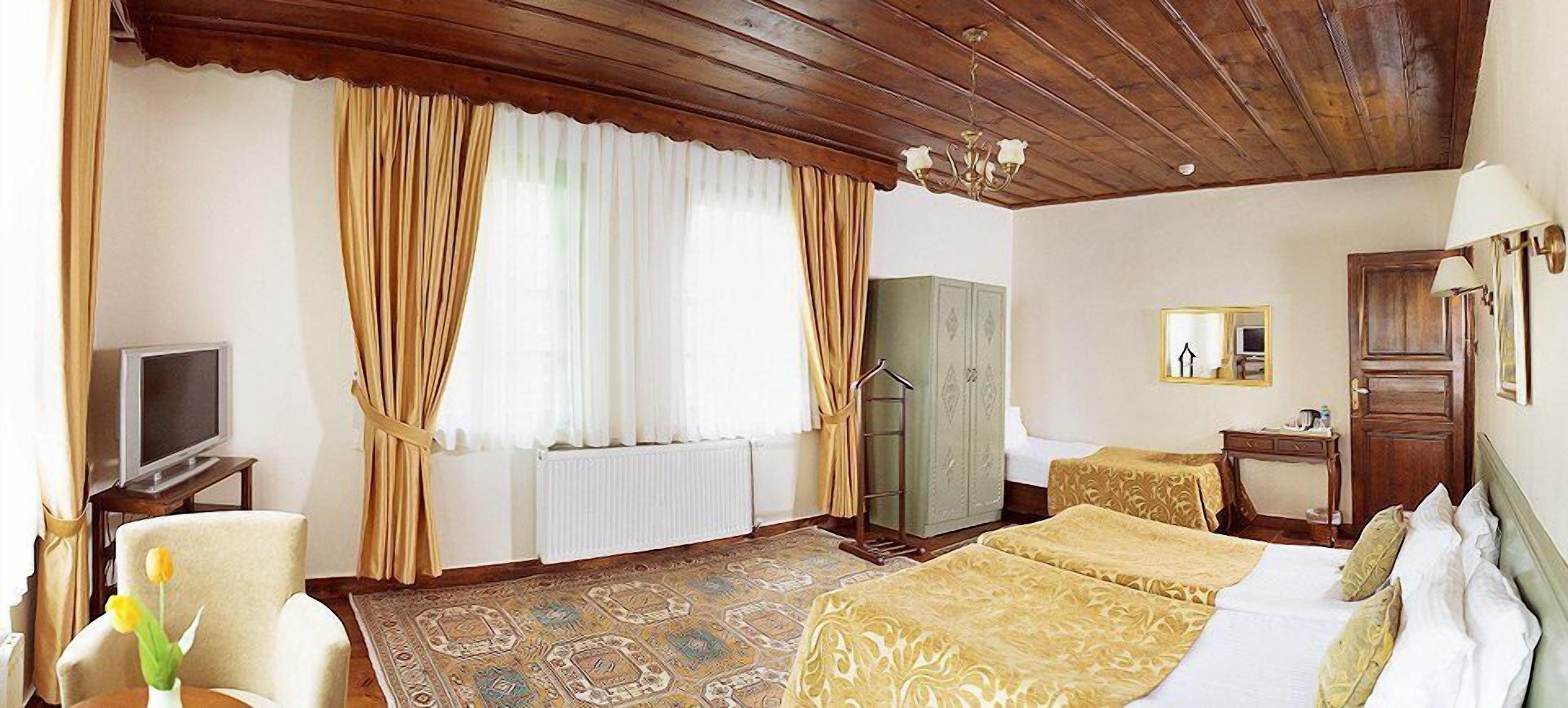 A hotel room with a bed, a television, a desk, and a wardrobe.