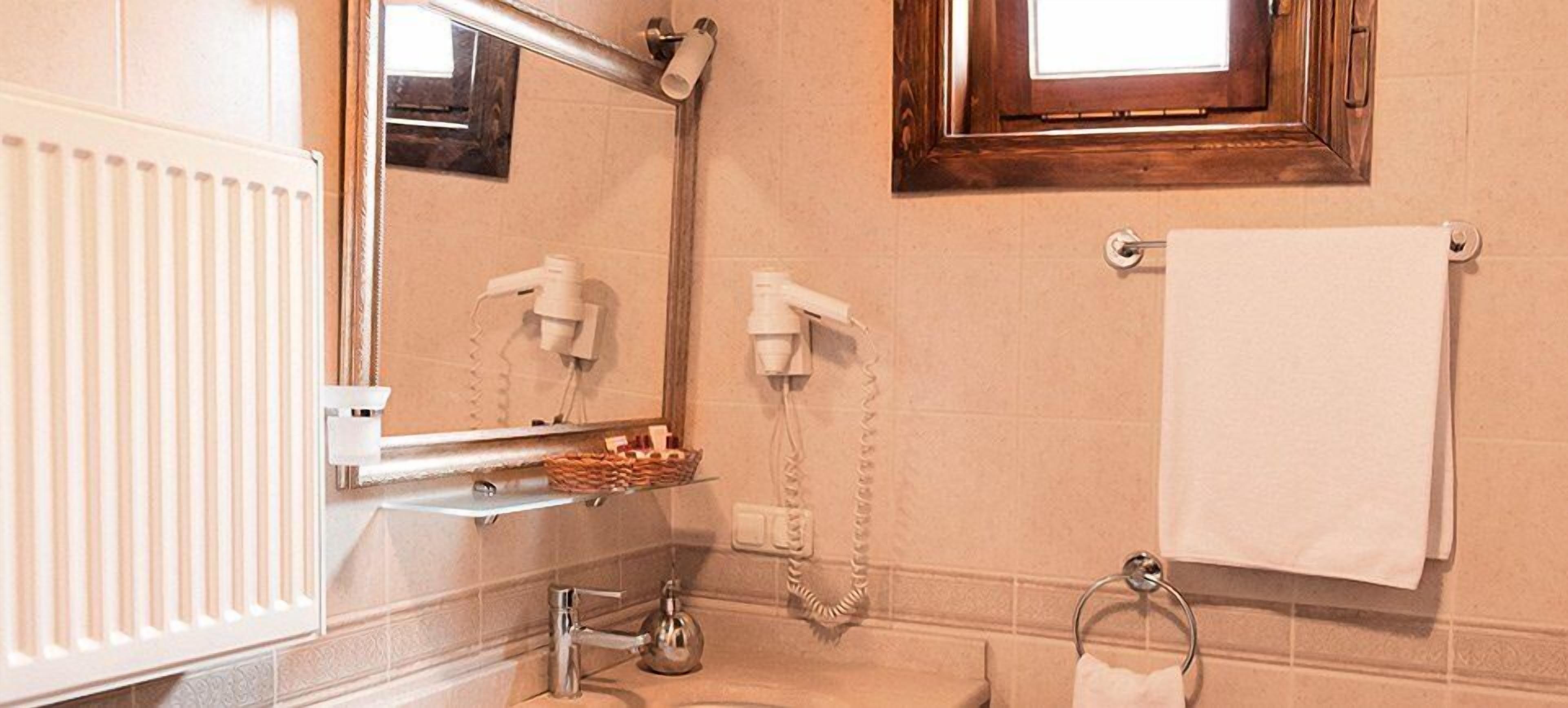 A bathroom with a white radiator, a mirror, a towel rack, and a shelf with toiletries.