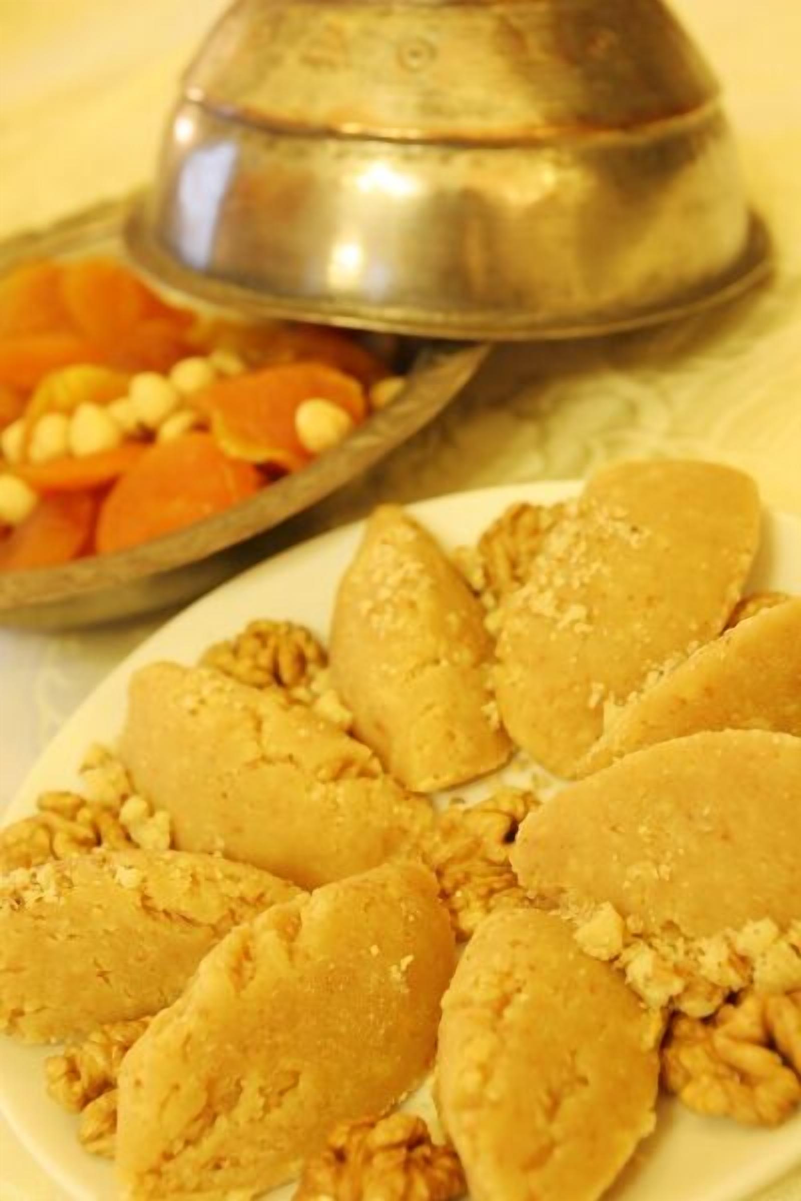 A plate of cookies with walnuts and a metal bowl in the background.