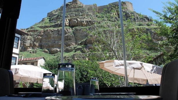 Una mesa con vista a una montaña rocosa y un edificio al fondo.