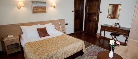 Une chambre à coucher avec un grand lit, des tables de chevet, une commode, un bureau, une chaise et un miroir.