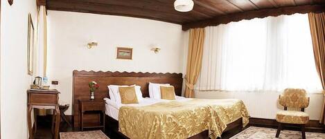 A hotel room with a wooden bed, a nightstand, a chair, and a window with curtains.