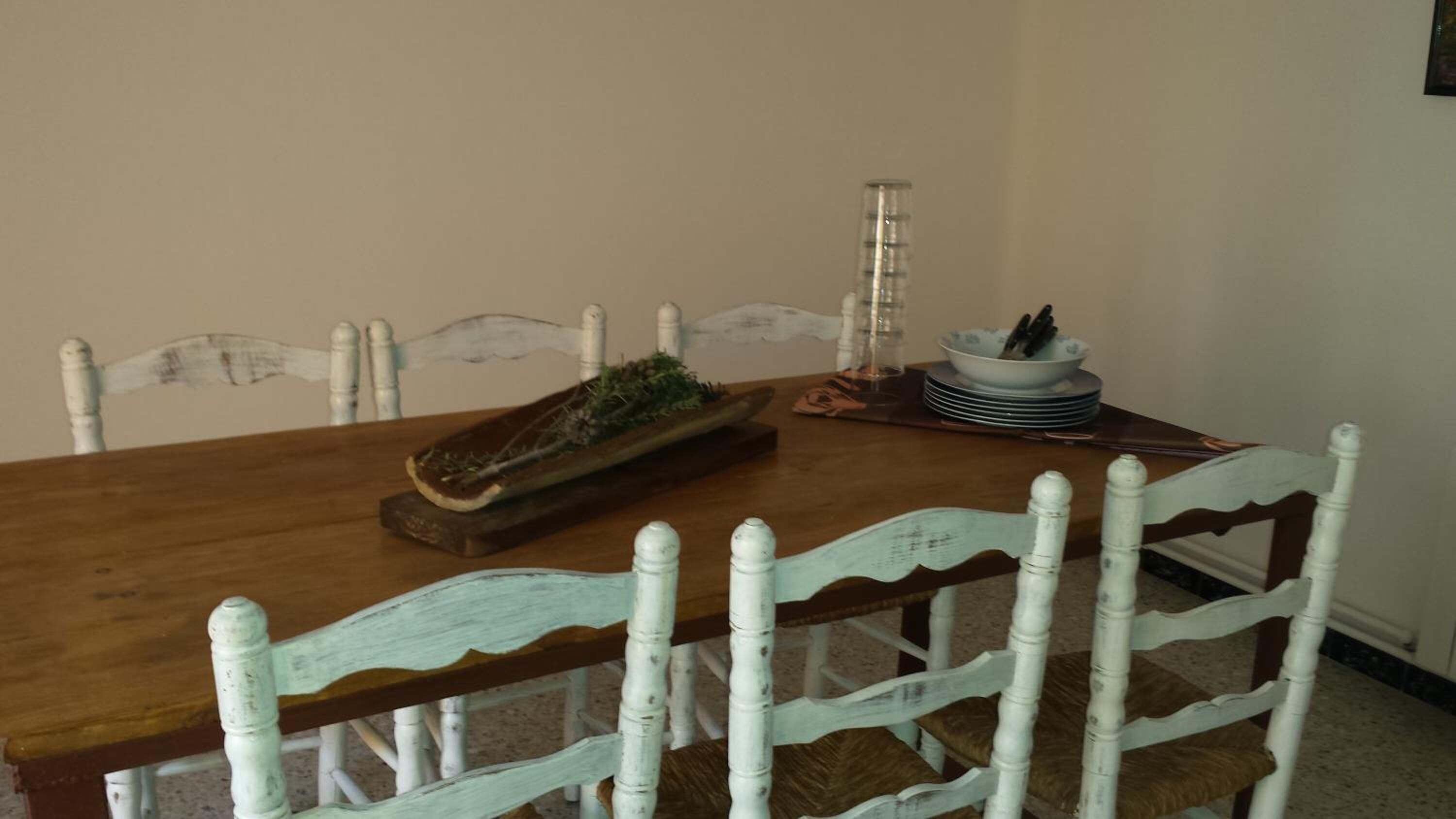 A dining table with a wooden top and white chairs with a distressed finish.