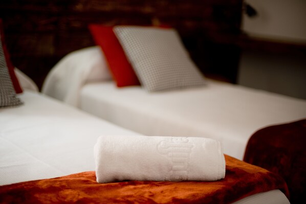 A neatly made bed with a white towel and a red pillow. - Apartaments MO (Monistrol de Montserrat)