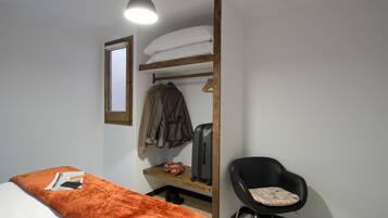 A compact room with a bunk bed, a small desk, a chair, and a hanging light fixture.