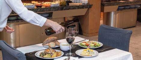A buffet setup with various dishes and a person pouring wine.