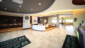 Un hall d’hôtel doté d’un plafond incurvé, d’un comptoir d’accueil, d  ’un espace salon et d’une horloge murale.