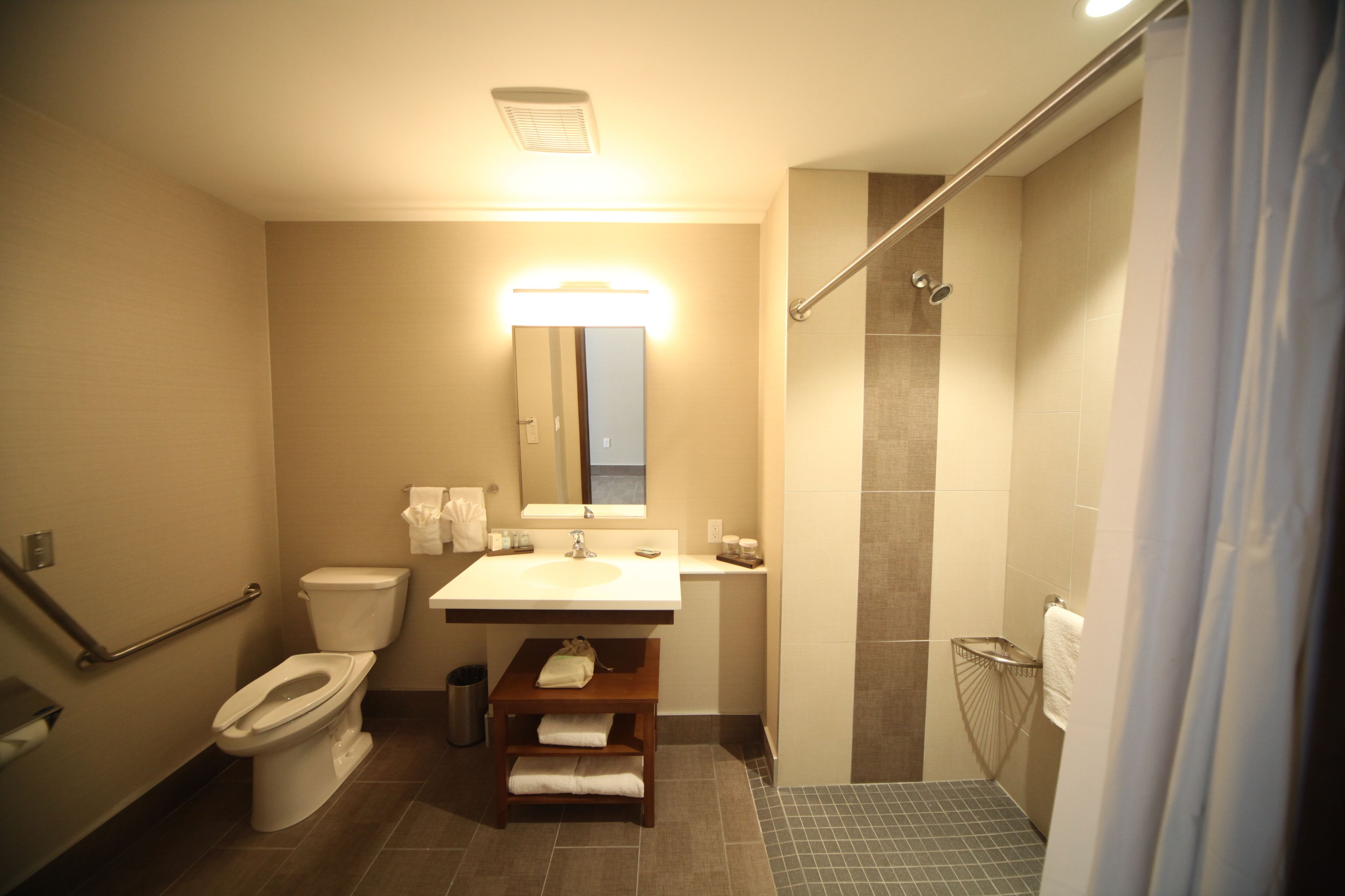 Un baño con inodoro, lavamanos, espejo y zona de ducha.