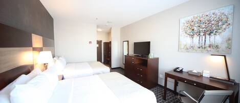 A hotel room with two beds, a desk with a chair, a television, and a painting on the wall.