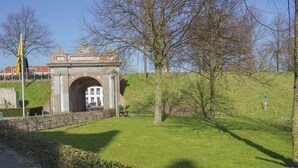 A grassy area with a stone archway leading to a building. - Holiday Home Koewacht near Seaside (Koewacht)