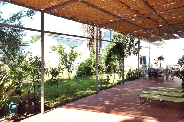 A covered outdoor area with a patio, chairs, and a table. - Belvilla by OYO Pompei (Trecase)