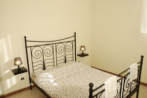 A single bed with a metal frame, two bedside lamps, and a floral-patterned bedspread. - Belvilla by OYO Pompei (Trecase)