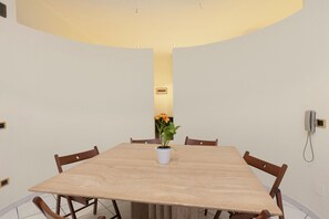A dining area with a large rectangular table, six wooden chairs, and a potted plant with yellow flowers. - Belvilla by OYO Pompei (Trecase)