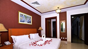 A hotel room with a large bed, a bedside telephone, and a framed picture on the wall. - Karan Sharq for Hotel Apartments Company (Al Jubail)