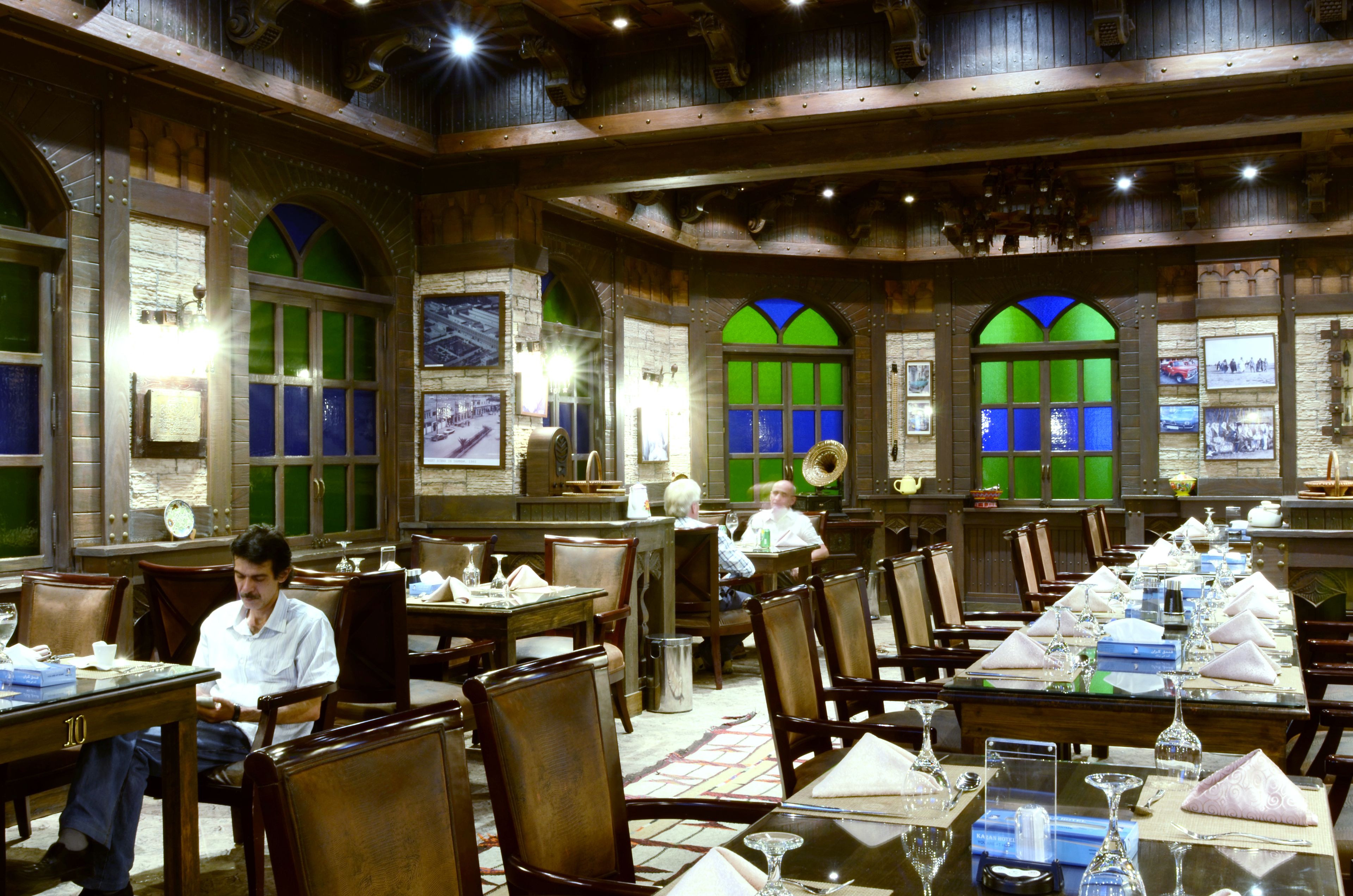 A restaurant with wooden interior, multiple tables set for dining, and framed pictures on the walls.