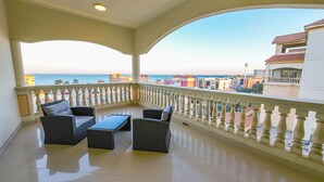 A balcony with a view of the sea and buildings, furnished with a sofa and a table. - Karan Sharq for Hotel Apartments Company (Al Jubail)