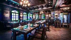 A restaurant with multiple tables set for dining, wooden beams on the ceiling, and a vintage decor style. - Karan Sharq for Hotel Apartments Company (Al Jubail)