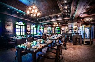 A restaurant with multiple tables set for dining, wooden beams on the ceiling, and a vintage decor style.